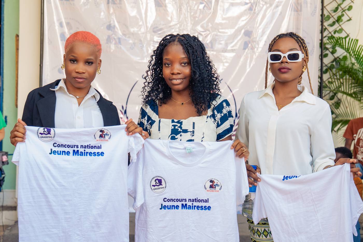 Trois participantes montrent les t-shirts du concours